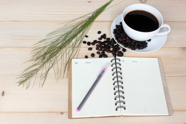 Sıcak kahve ve ahşap tahta üzerinde not defteri ile fasulye.