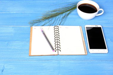 Mavi renk ahşap tahta üzerinde sıcak kahve defter ve Smartphone.