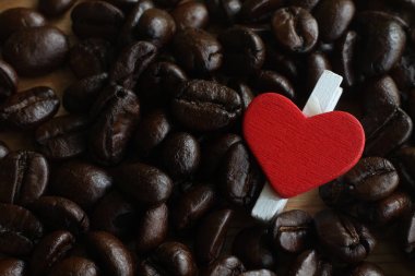 kahve çekirdekleri üzerinde clothespin ve kırmızı kalp.