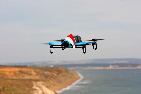 Blå Drone Med Jul Hatt Flyga Över Klippa — Stockfoto