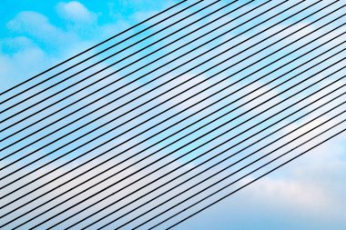 Paralel guyes çapraz olarak mavi ve bulutlu gökyüzü karşı bulunan askılı köprü. Riga, Letonya köprünün mimari ve metal constructure