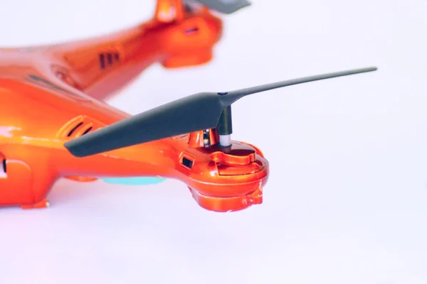 Close up view of a black propeller which mounted on the orange drone isolated on white. Drone is used for recreational, commercial, scientific, agricultural, aerial imagery, etc