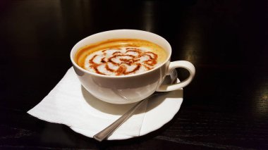 Koyu ahşap masa üzerinde sütlü latte veya cappuccino kahve fincan