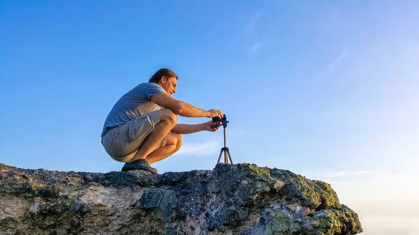 Travel videographer making video on the top of the cliff during sunset time