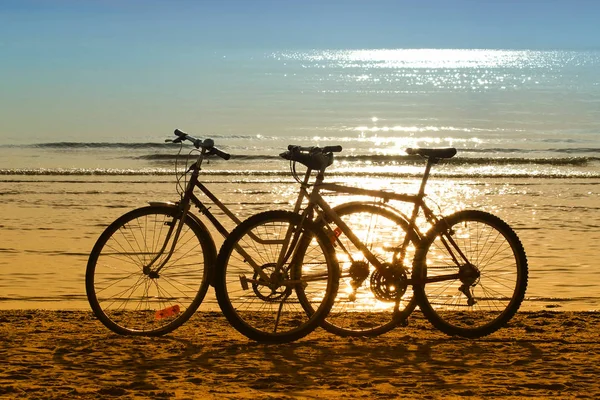 Dwa Rowery Sylwetki Stojące Piasku Pobliżu Brzegu Wody Plaży Piękne — Zdjęcie stockowe