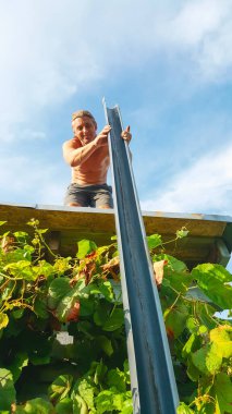 Kır evinin çatısında çalışan işçilerin kullandığı boru tesisatı. Mavi bulutlu gökyüzünde izole edilmiş. Yaz mevsiminde ev ve bahçe onarım işleri