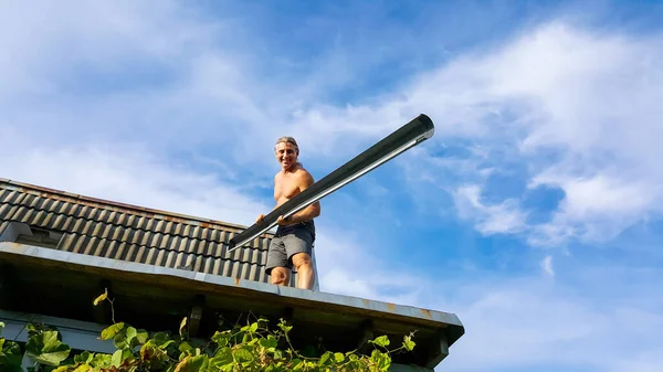 男工在房顶上安装了下水管道 在蓝色的多云的天空上与世隔绝 夏季家庭和花园维修工作 — 图库照片