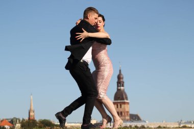 Yaşlı şehrin arka planında tango yapan genç bir çift. Mavi gökyüzünde ıssız