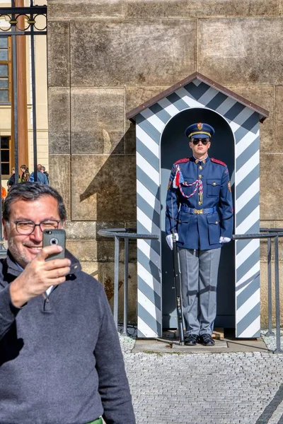 Des touristes non identifiés sont photographiés avec les gardes aux portes du château de Prague . — Photo