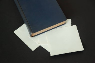 Vintage resimleri çerçeve Lacivert bir kitap ile siyah bir arka plan olarak bir yığın. Kendi fotoğraf veya metin ekleme.