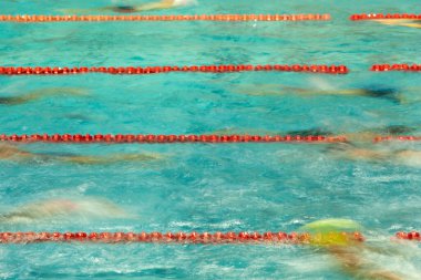 Yarışmacı yüzücüler yarıştan önce havuzda ısınırlar. Görüntü, hareket bulanıklığını göstermek için uzun pozlama kullanılarak çekildi.
