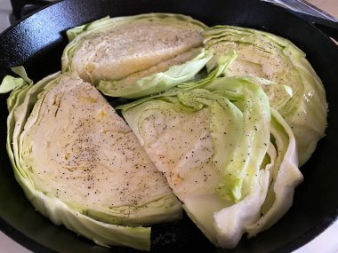 Tuz ve biberli yeşil lahana sobanın üzerindeki dökme demir tavada pişiriliyor..