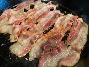 Domuz pastırması ocakta pişiyor. Siyah dökme demir tavada.