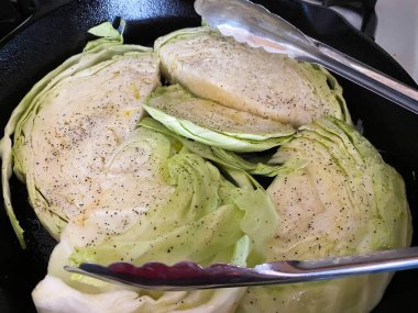 Tuz ve biberli yeşil lahana sobanın üzerindeki dökme demir tavada pişiriliyor..