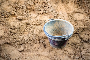 İnşaat site kova kum, kullanıma hazır bir yığının üstüne yerleştirilen siyah renkte.