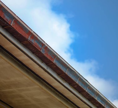 Alt görünümü, eski ve paslı mavi gökyüzü arka plan ile şirketten bir kırık çatı oluk.