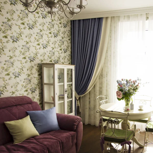 Sunny living room with big bouquet on round table, interior in Provence style