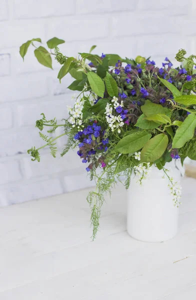 Wild forest meadow bouquet of cherry, lungwort, wild herbs in can on white background