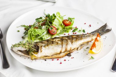 Limon ve beyaz tabakta restoranda taze sebze pişmiş balık
