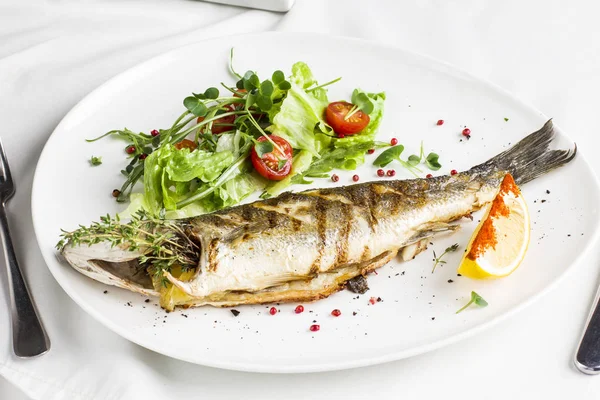 Limon ve beyaz tabakta restoranda taze sebze pişmiş balık