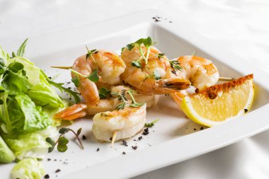 Kaplan karides şiş limon ve beyaz bir tabak üzerinde yeşillik üzerinde