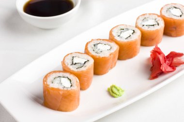 Japon Suşi rulo ile somon, soya sosu ile hizmet veren, wasabi ve zencefil üzerinde beyaz arka plan