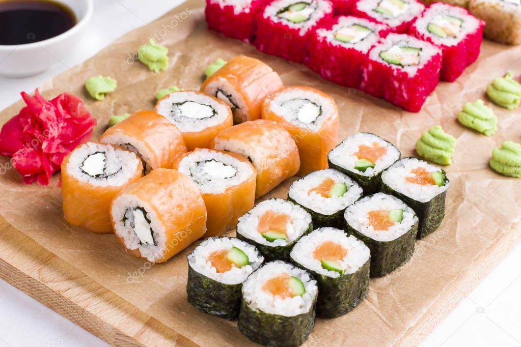 Set of different types of Japanese sushi rolls on wooden Board
