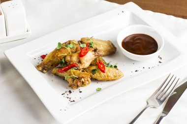 Fırında tavuk kanadı chili biber ve acı sos beyaz plaka üzerinde ızgara