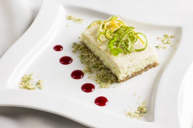 Limon ve kireç ile çiğ gıda tatlı pasta beyaz plaka üzerinde meyve şekerlenmiş