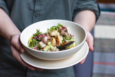 Deniz ürünleri midye, ahtapot ve derin plaka kadın elinde taze sebze ile sıcak salata