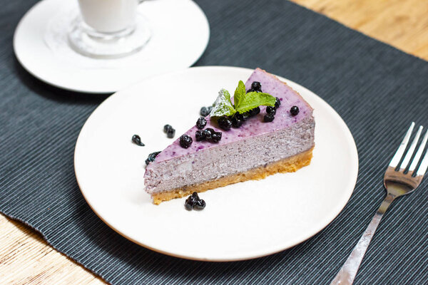 Blueberry cheesecake with berries and mint with coffee latte on the table