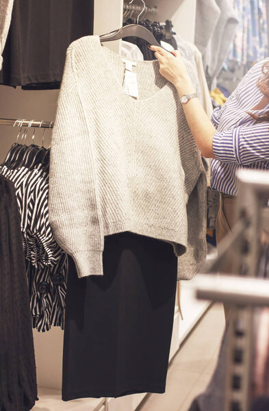 Young woman stylist shopper chooses clothes in the store