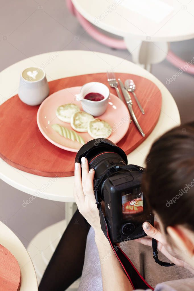 Young woman food photographer shoots Breakfast in cafe, workflow