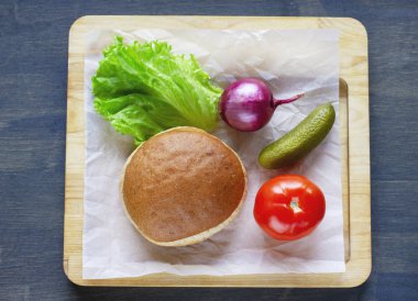 Vejetaryen Burger topuz, soğan, marul, domates ve salatalık turşusu ahşap tahta üzerinde için malzemeler