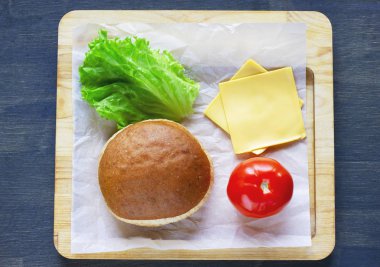 Vejetaryen çizburger topuz, soğan, marul, domates ahşap tahta üzerinde için malzemeler