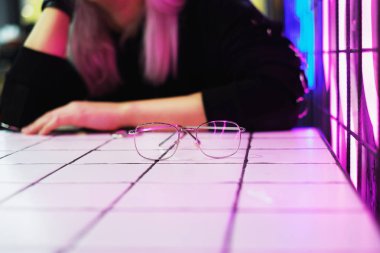 Metal çerçeve gözlük neon ışık kafede kız arka plan üzerinde yansıtır.