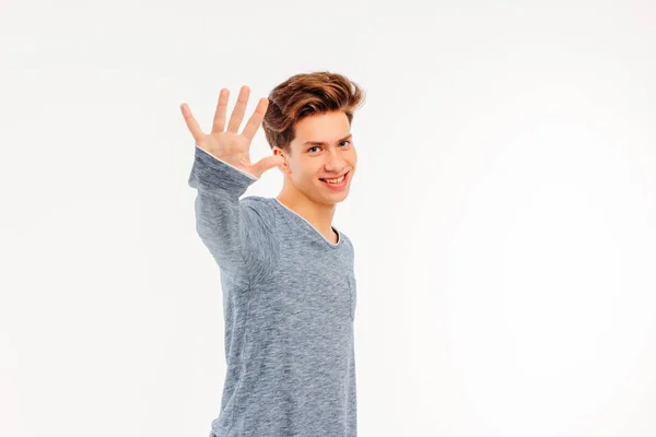 Sorrindo jovem recebe dizendo adeus à mão no fundo branco — Fotografia de Stock