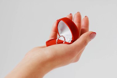 Kadın el ile nişan yüzüğü izole gri arka plan üzerinde kırmızı bir kutu içinde