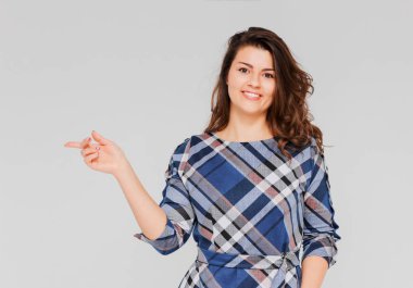 İzole sağda gri arka plan güzel pozitif gülümseyen esmer kız ekose elbise ortaya