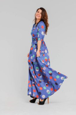 Arka plan, tam uzunlukta portre genç gülümseyen esmer kadın Grey uzun mavi elbiseli kıvırcık saçlı Sevimli izole