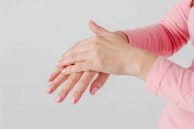 Hassas güzel kadınların elleri pembe manikür leke kremi el masaj gri arka plan üzerinde izole bakım ile yakın çekim