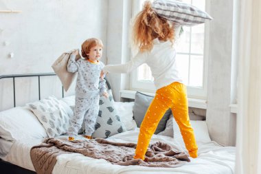 Kız ve erkek kardeşim yatakta yastık ile oynarken pijama