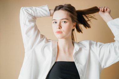 Güzel manken çıplak kız kameraya bakarak beyaz gömlekli bej renkli arka plan üzerinde izole.                               