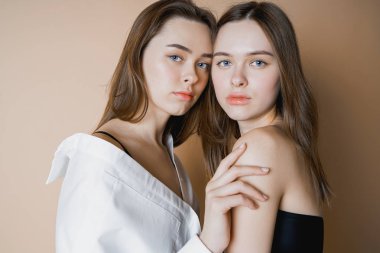 İki kız kardeş ikiz güzel çıplak kız kameraya arıyorum bej renkli arka plan üzerinde izole moda modelleri                               