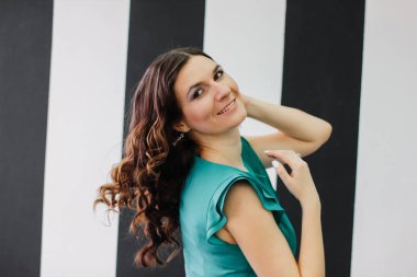 Mutlu hareket esmer kıvırcık saç stili siyah ve beyaz duvar zemin üzerine yeşil aqua nane kokteyli elbiseli Genç kadın kız Sevimli güzel dans