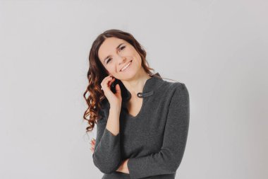 Gri arka plan üzerinde izole rahat elbiseli genç gülümseyen esmer kıvırcık saç stili kadın Bayan portresi