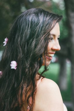 Güzel büyüleyici portre genç kadın kız pembe çiçekli karanlık kıvırcık uzun saç stili ile gülümseyen bahar yaz saati