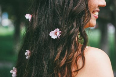 Güzel büyüleyici portre genç kadın kız pembe çiçekli karanlık kıvırcık uzun saç stili ile gülümseyen bahar yaz saati