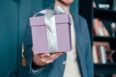 Mavi arka plan üzerinde genç attracrive birinin elinde gri gümüş kurdele ile hediye kutusu