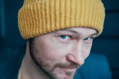 Çekici yetişkin sakallı adam hipster sarı şapkalı kamera ve smilingon mavi duvar arka plana bakarak yakın çekim